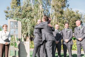 I love it when the groomsmen hug it out with the groom as they walk up the aisle to stand alongside him. Photo by Katie Jackson